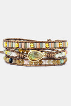 Front studio view of a woman's wrist wearing the gorgeous Stella Stone Cuff, showcasing the three layers of handmade natural crystal agate beads.. Multistrand beaded bracelet with a central gold teardrop bead on a white background