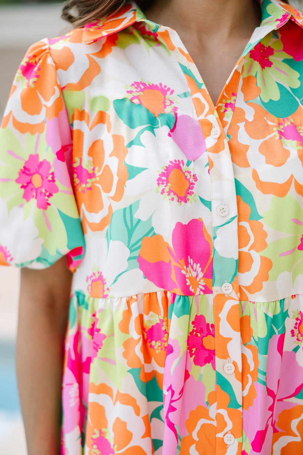 Close-up of floral mini dress showing collared neckline, button front, and gathered tier.