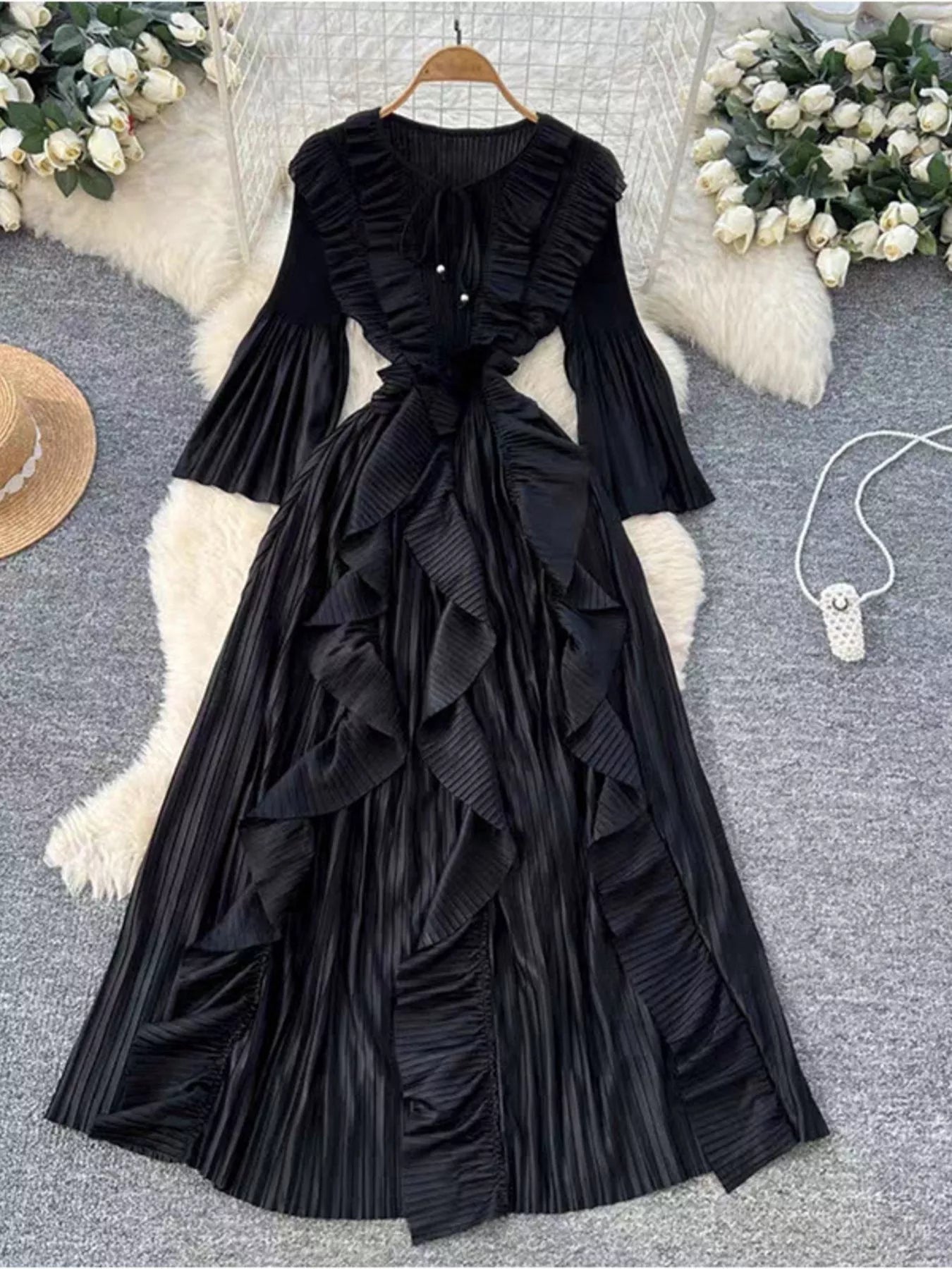 Black ruffled dress on a hanger with decorative elements in the background