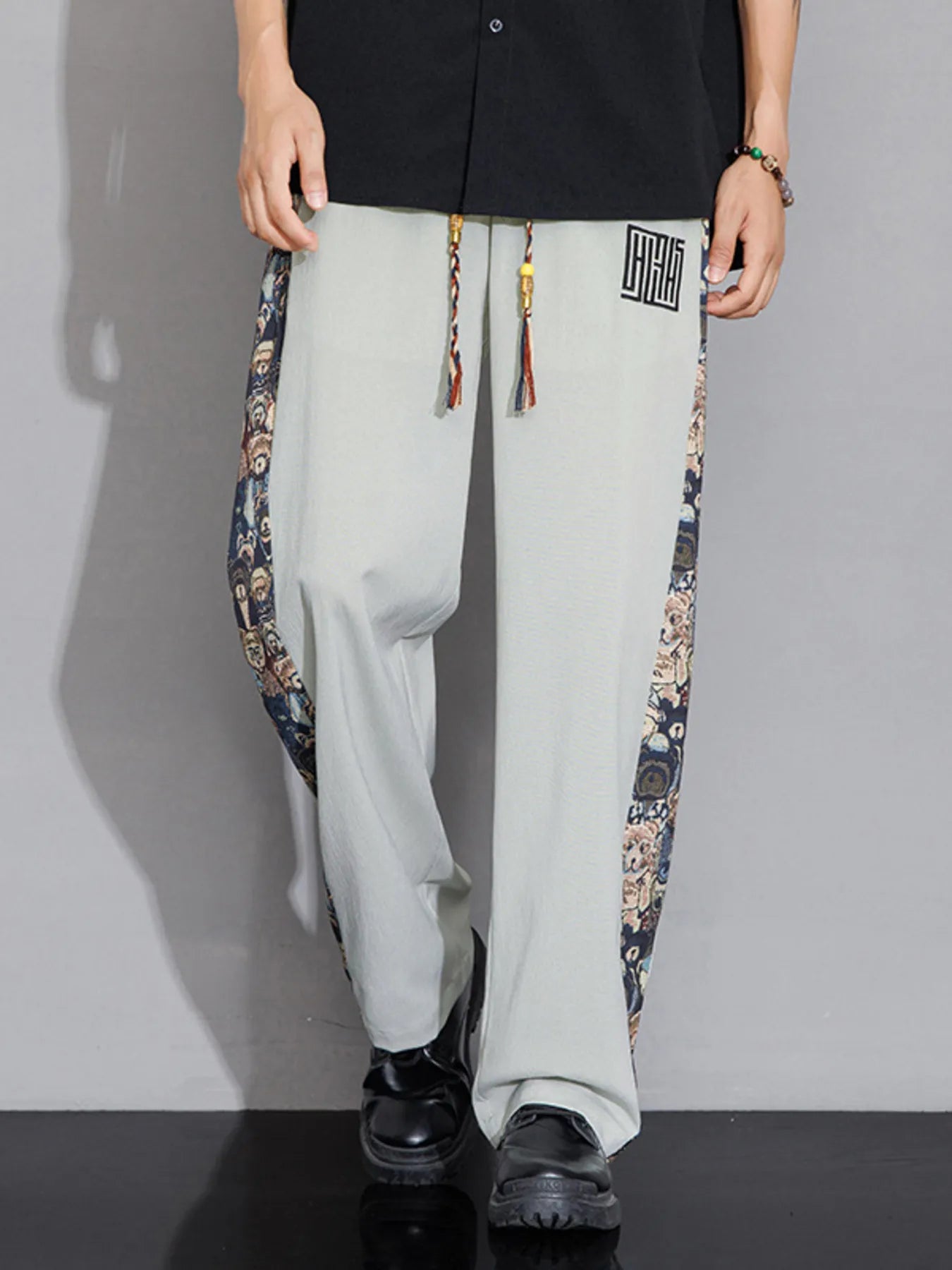 Light gray pants with colorful side panels worn by a person on a gray background
