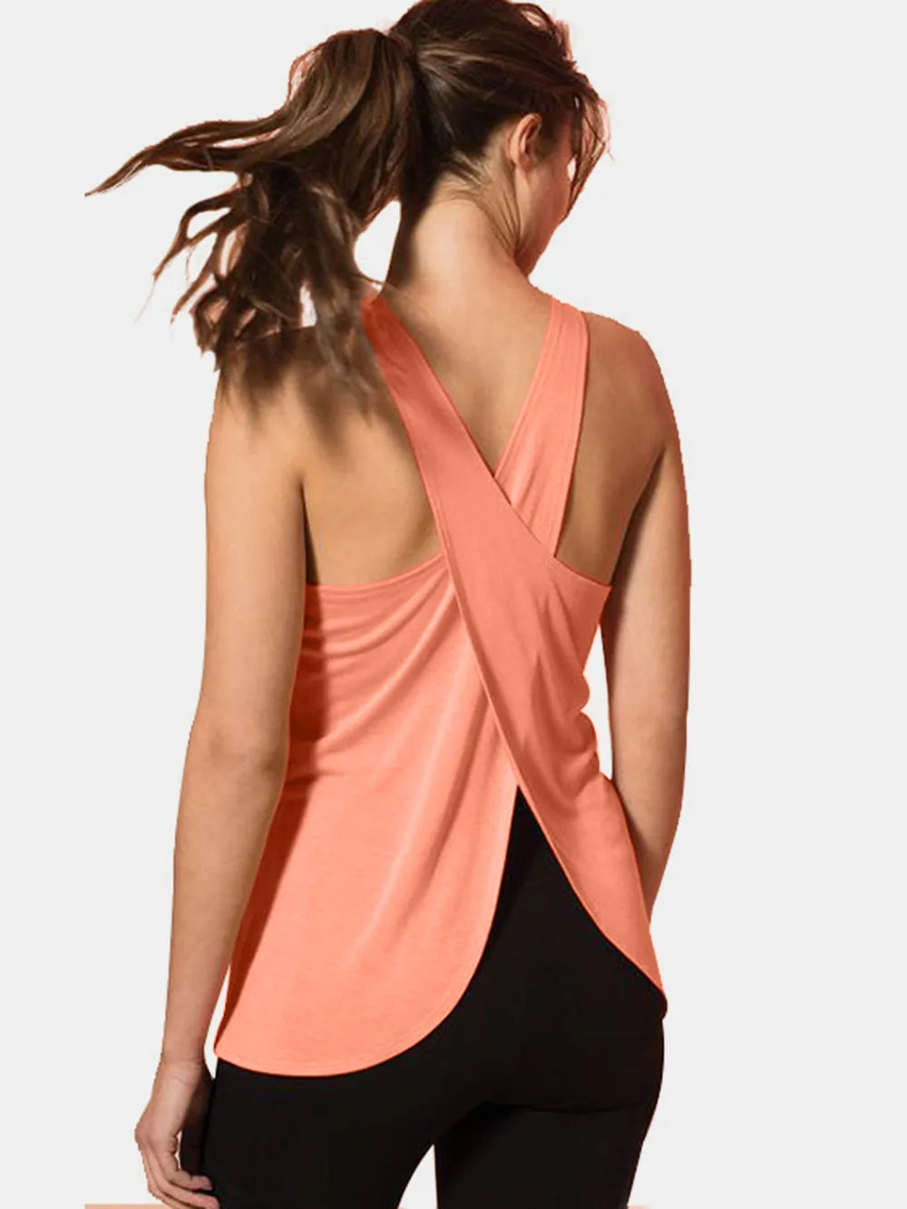 Front view of a model styling the premium coral pink crisscross scoop neck active tank top.