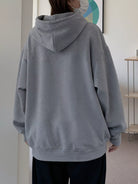 back view of a person wearing a gray hoodie in an indoor setting