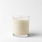 White candle in a clear glass container on a white background