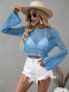 Woman wearing a blue crochet top and white shorts with a straw hat on a gray background