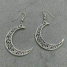 Silver crescent moon earrings with intricate designs on a gray background
