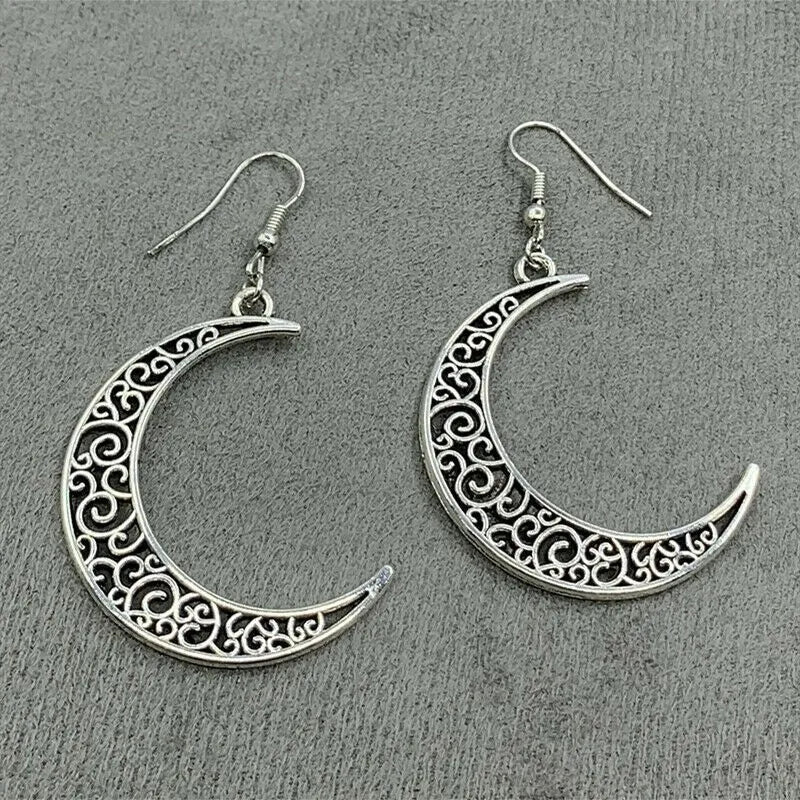 Silver crescent moon earrings with intricate designs on a gray background