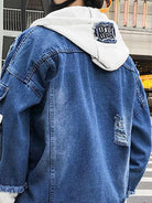 A person wearing a blue denim jacket with a white hood, photographed from the back. The jacket has a distressed patch on the lower back and a white hood with a dark embroidered patch.