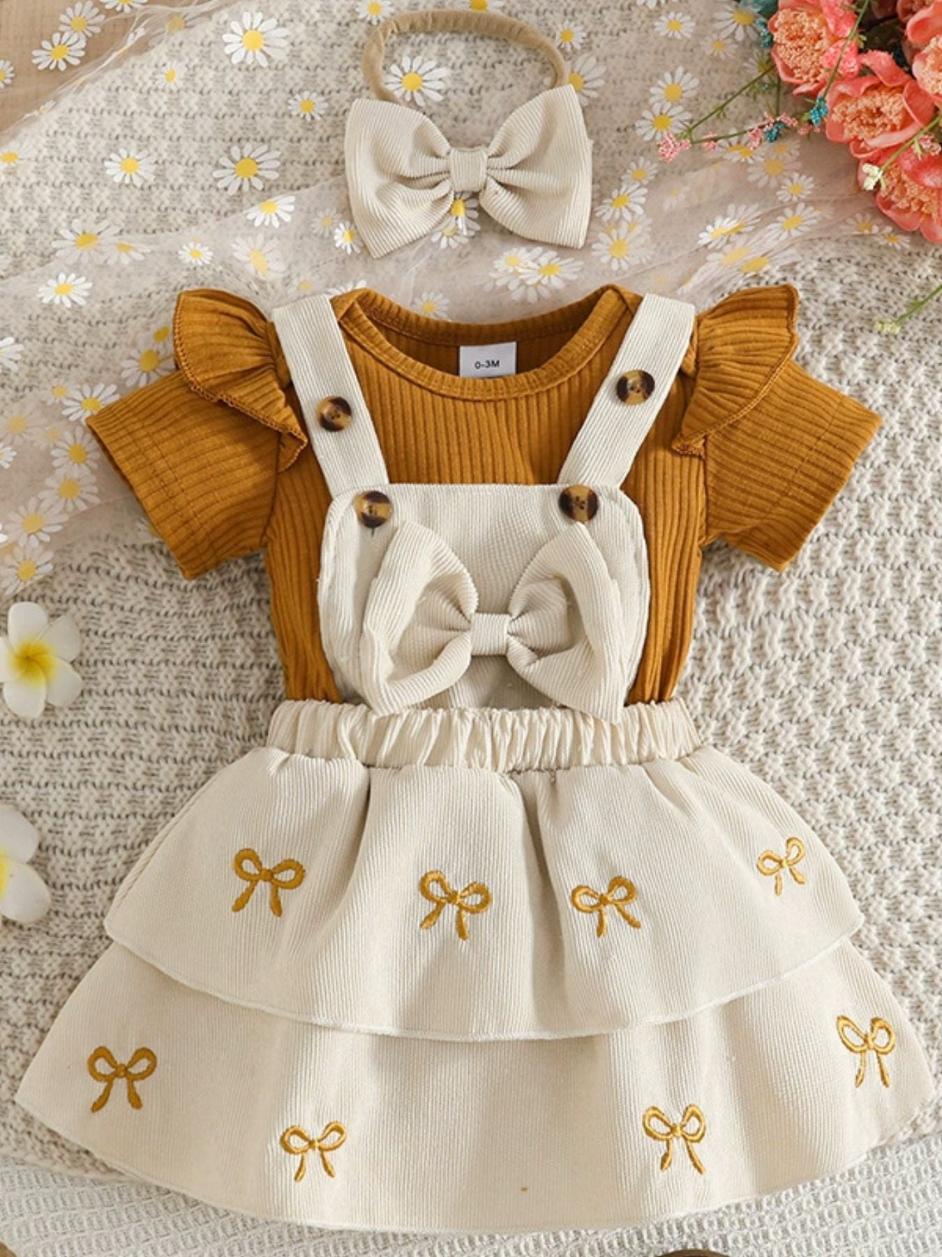 Children's outfit with mustard top and white skirt with bow designs on a floral background