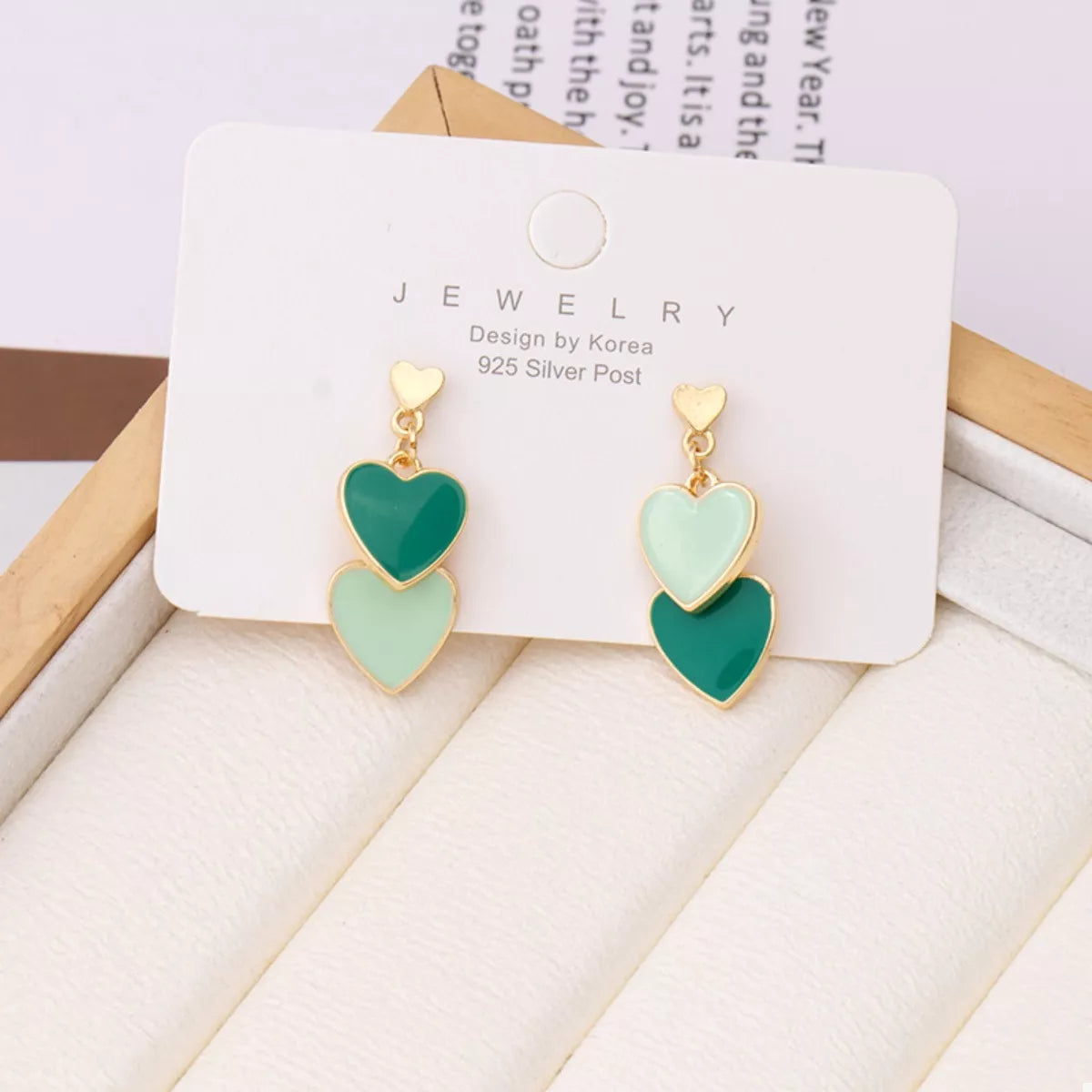 Green heart-shaped earrings on a jewelry card with a light background