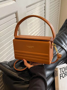 Brown handbag held by a person with a blurred background