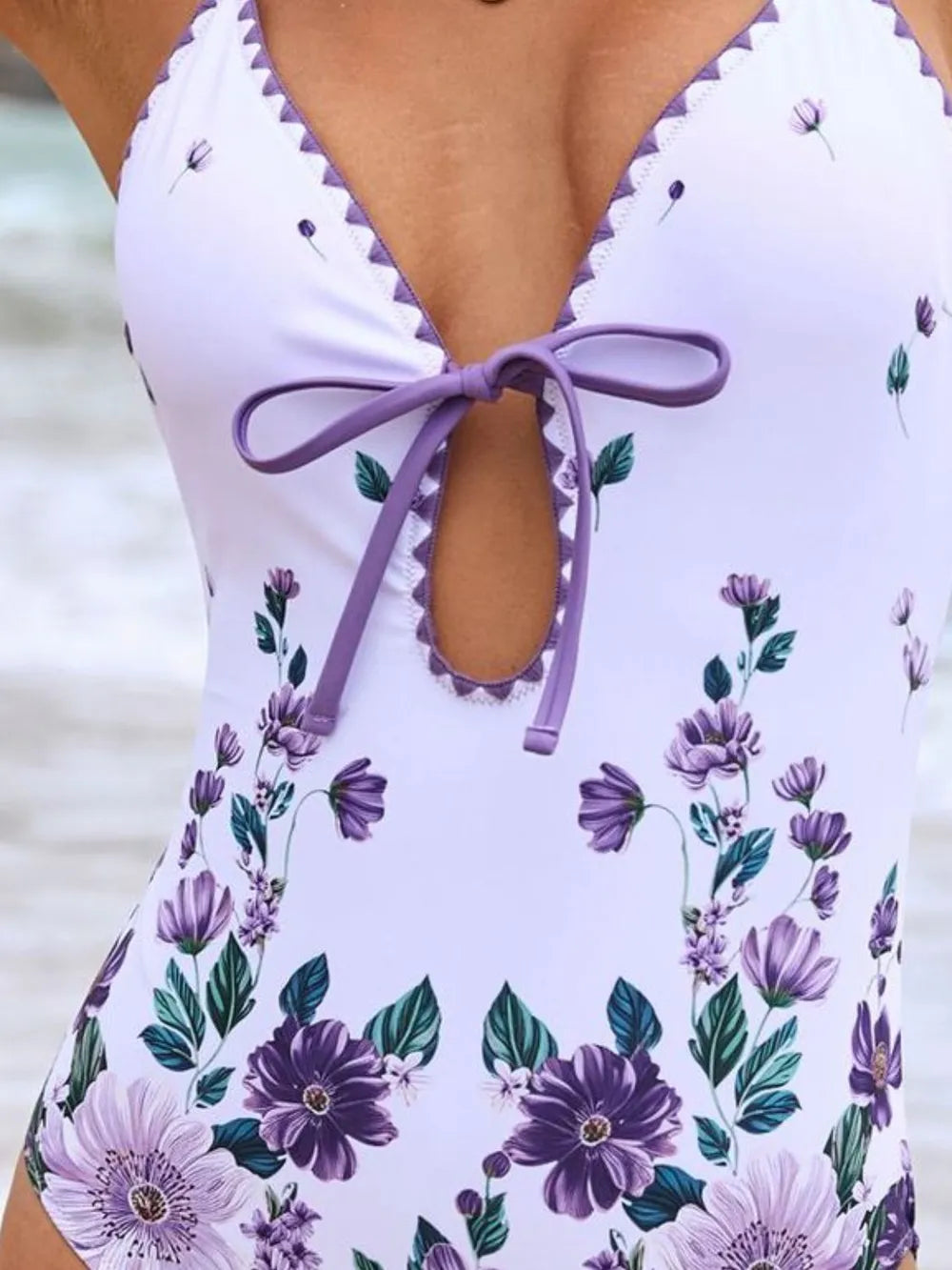 White swimsuit with purple floral pattern and tie back detail.