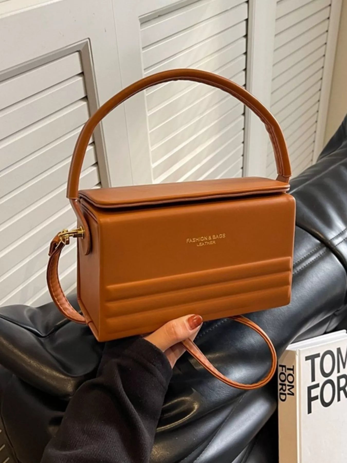Brown handbag held by a person with a blurred background