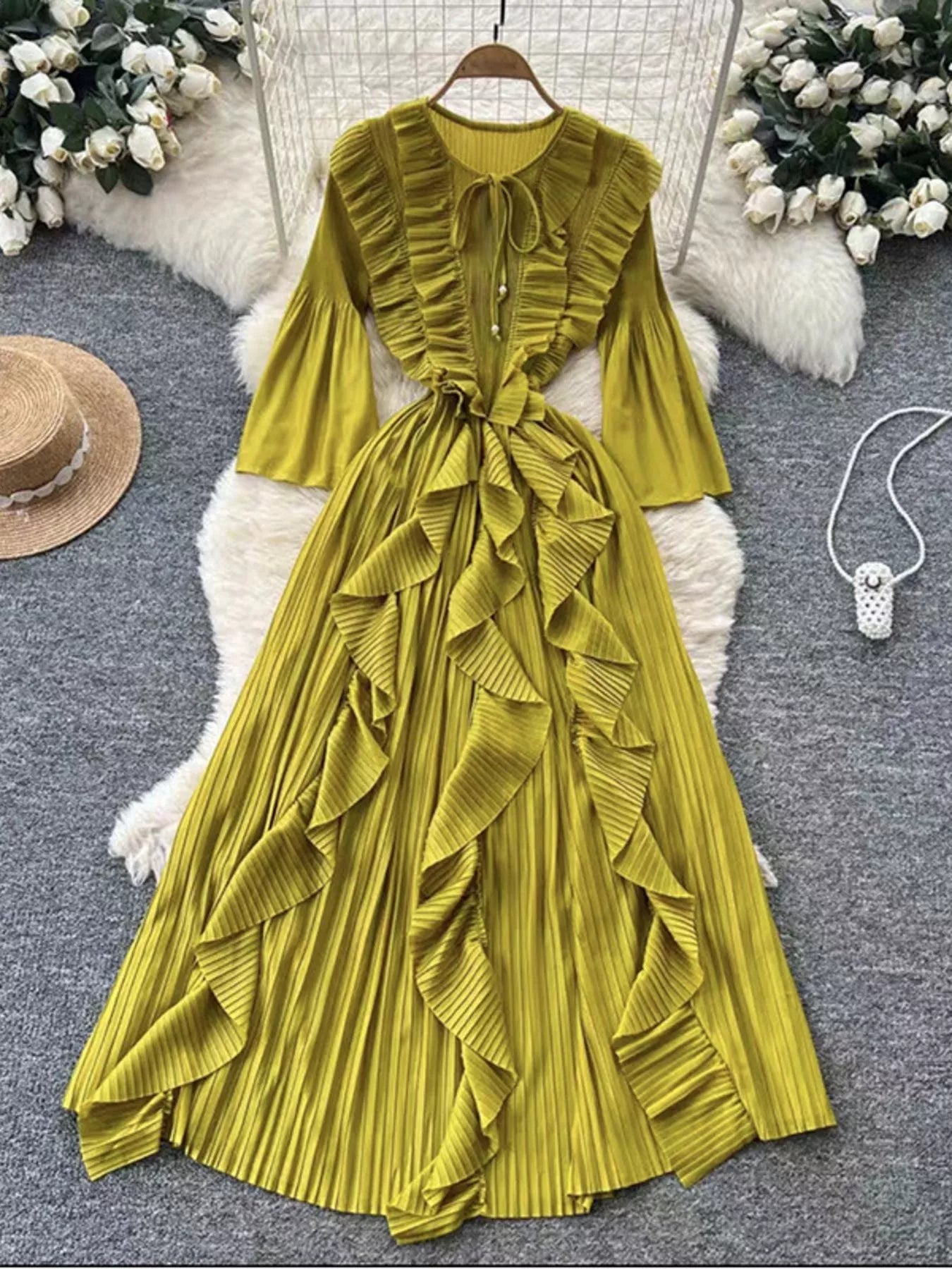 Yellow pleated dress on a hanger with decorative background