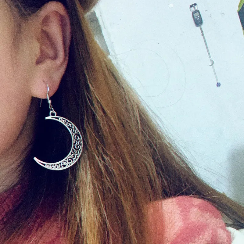 Close-up of a person wearing a silver crescent moon earring.