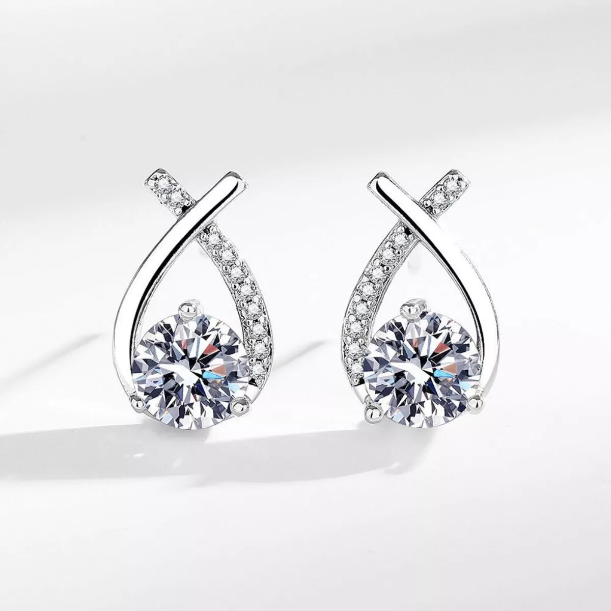Pair of silver earrings with clear gemstones on a white background
