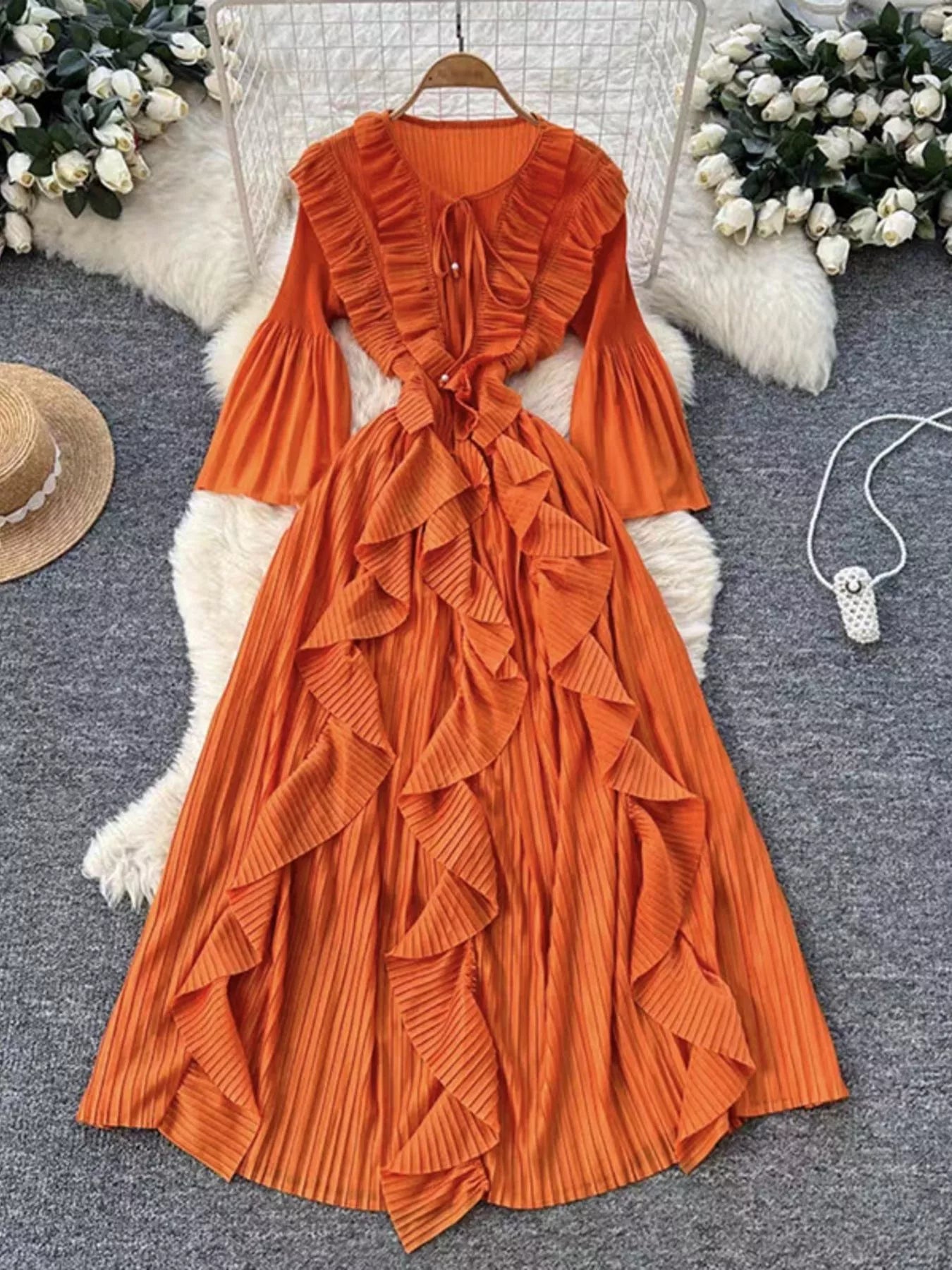 Orange ruffled dress on a hanger with decorative elements in the background