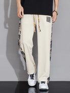 Person wearing cream-colored pants with colorful drawstring and patterned side panels on a gray background