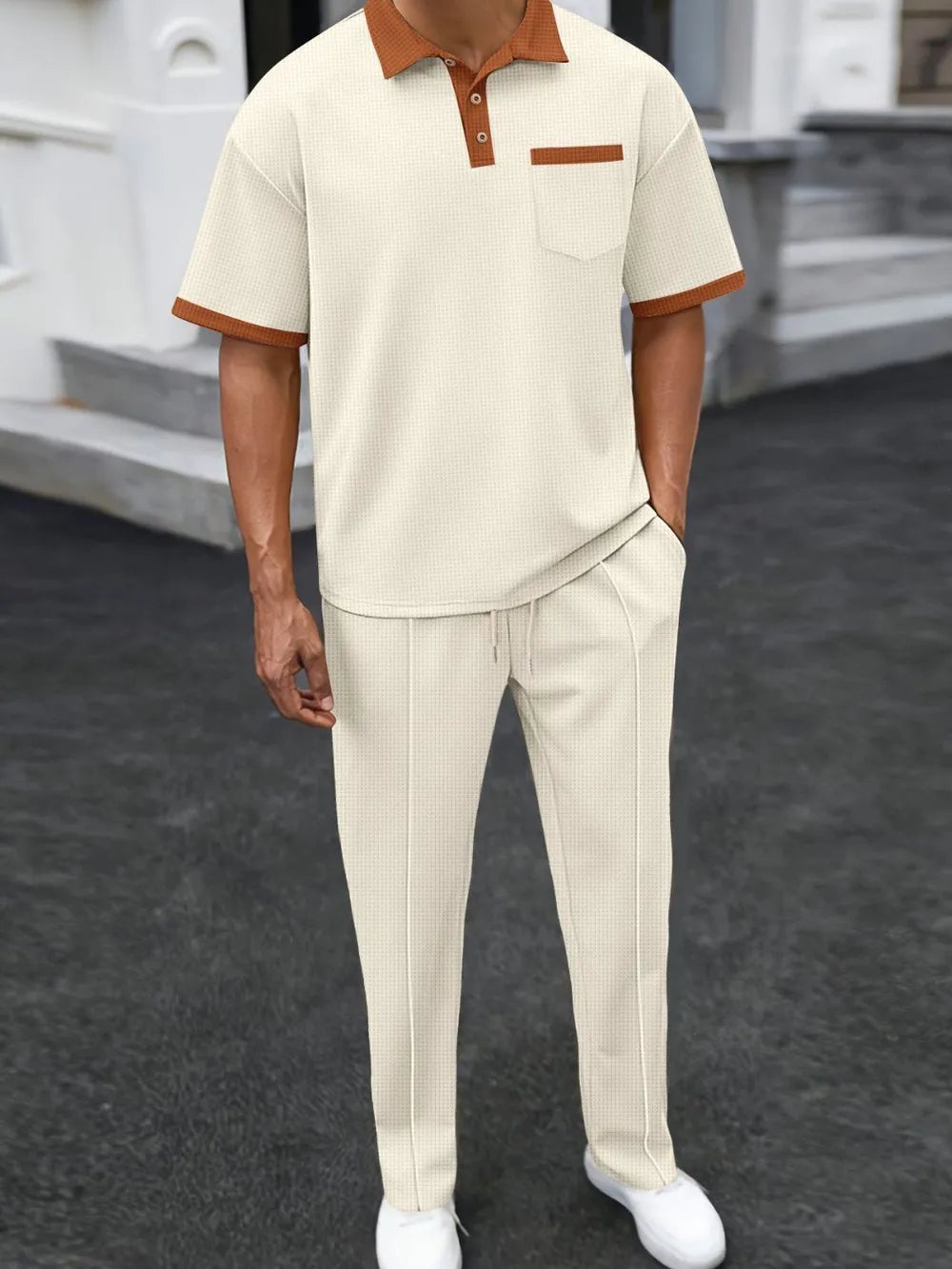 Person wearing a beige outfit with brown accents on a dark surface