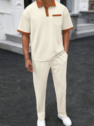 Person wearing a beige outfit with brown accents on a dark surface