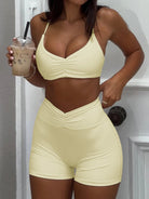 Person wearing a light yellow sports bra and shorts set, holding an iced coffee.