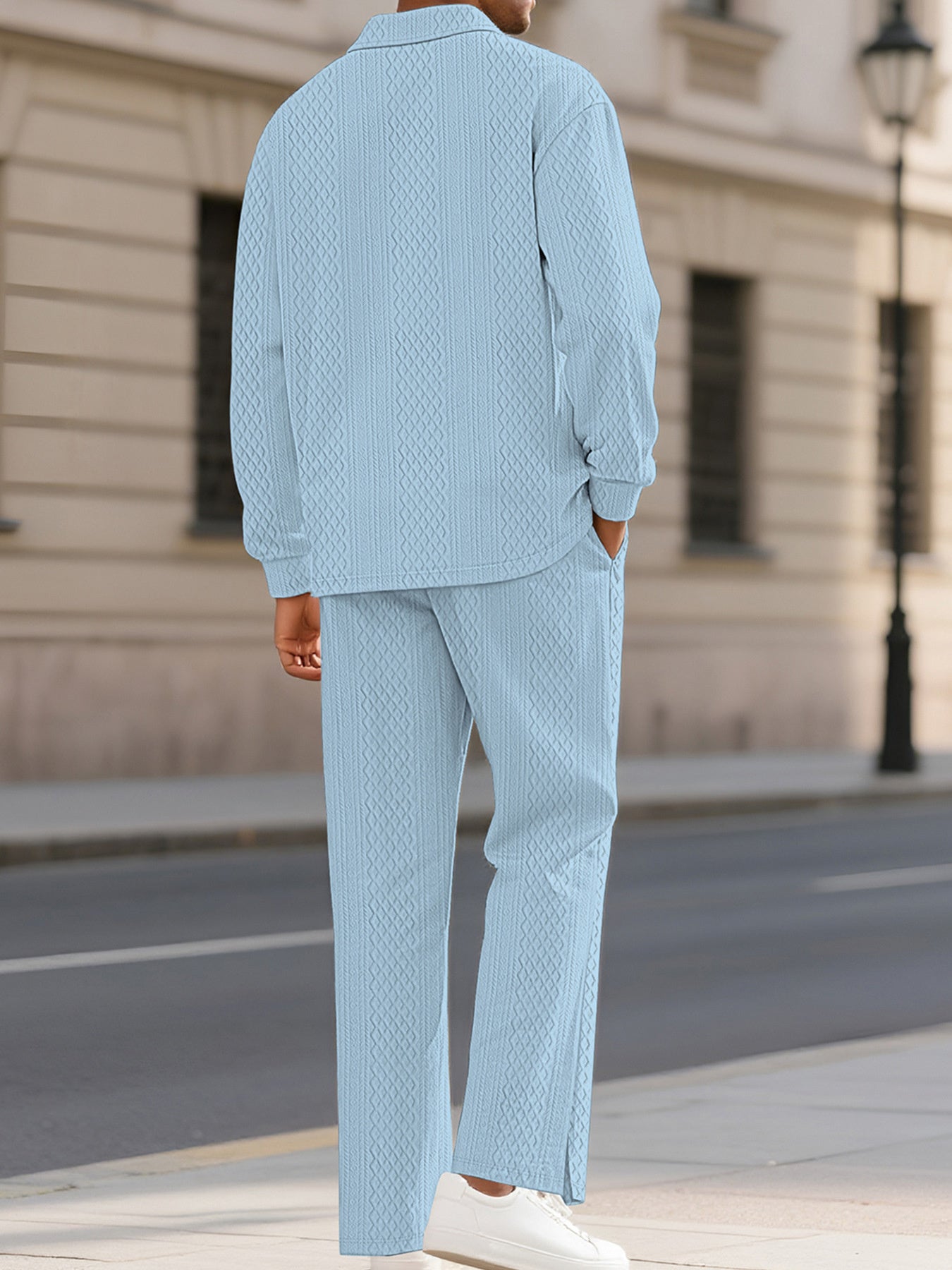 A man wearing a light blue textured two-piece lounge set with a long-sleeve shirt and matching trousers, standing on a city sidewalk.