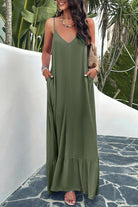 A woman wearing a matcha green backless maxi cami dress with pockets, standing near a tropical setting.
