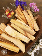 Palo Santo sticks in a wooden bowl with dried flowers on a wooden surface
