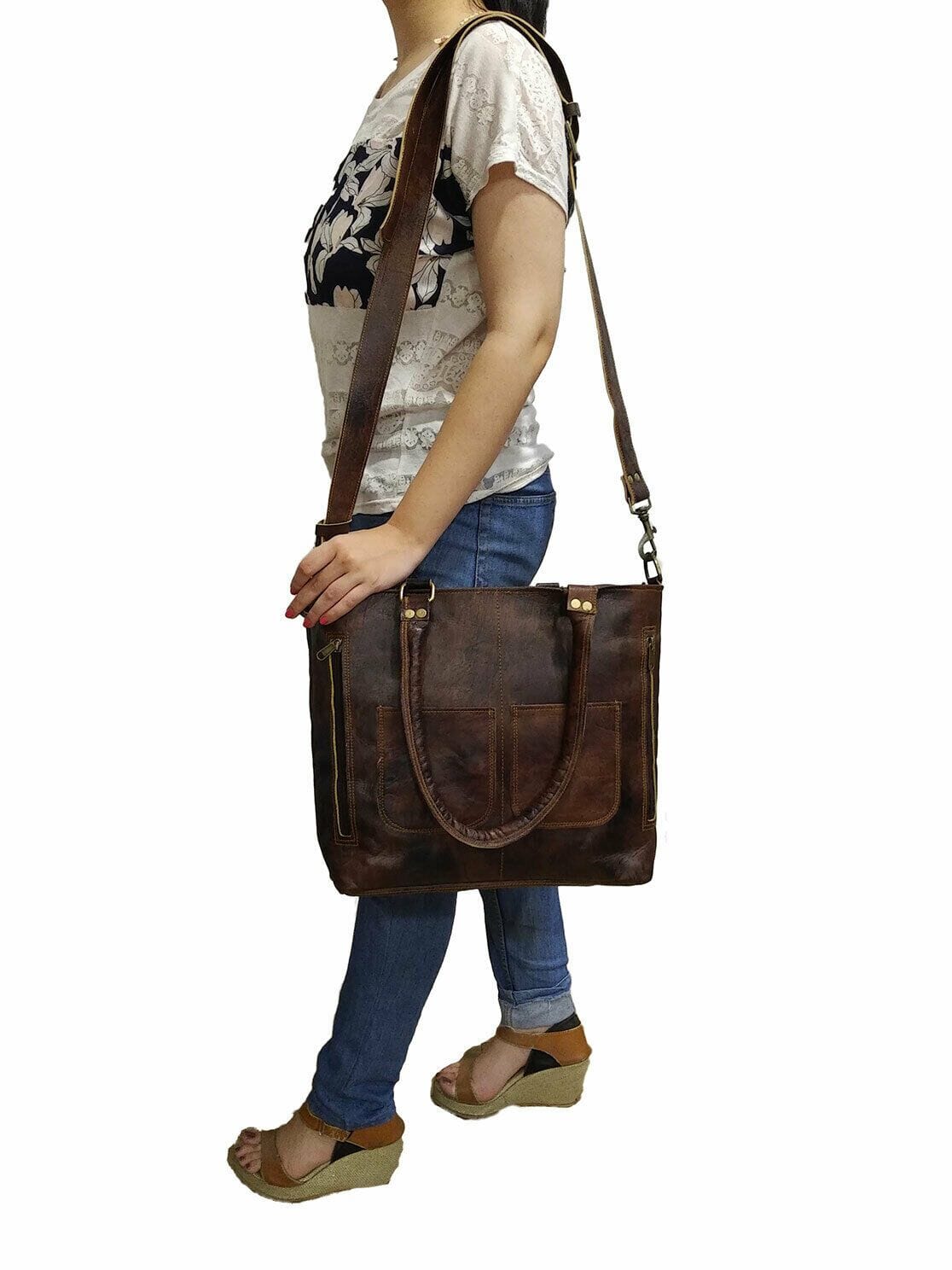 Person wearing a brown leather shoulder bag on a white background